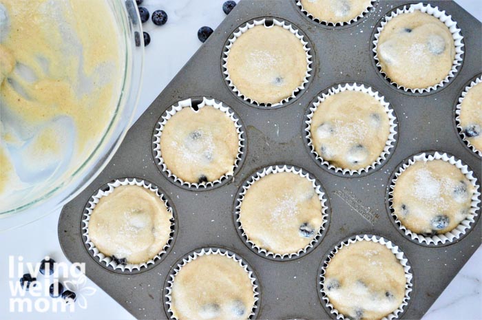 muffin tin with blueberry muffin batter with a muffin liner