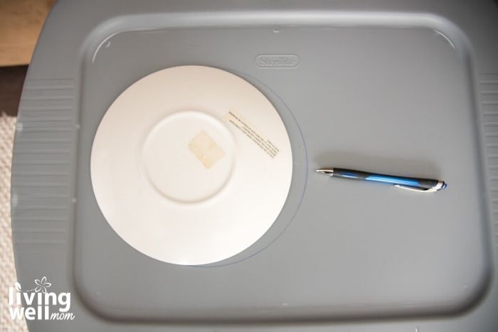 tracing plastic plate with pen on gray plastic bin