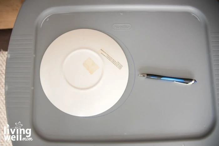 tracing plastic plate with pen on gray plastic bin