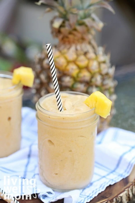 Mango pineapple smoothie poured into a mason jar with pineapple wedge on top