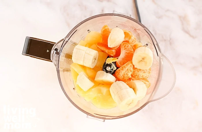 Arial view of a blender with banana, orange, and pineapple in it