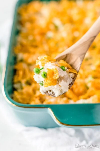 up close spoon holding chicken and rice casserole with the rest of the dish in the background