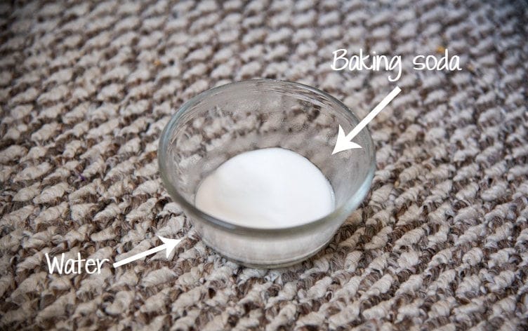 small glass bowl with baking soda and water on tan carpet for cleaning microfiber couch stain