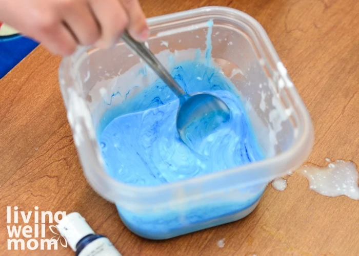 stirring together glue and blue food coloring