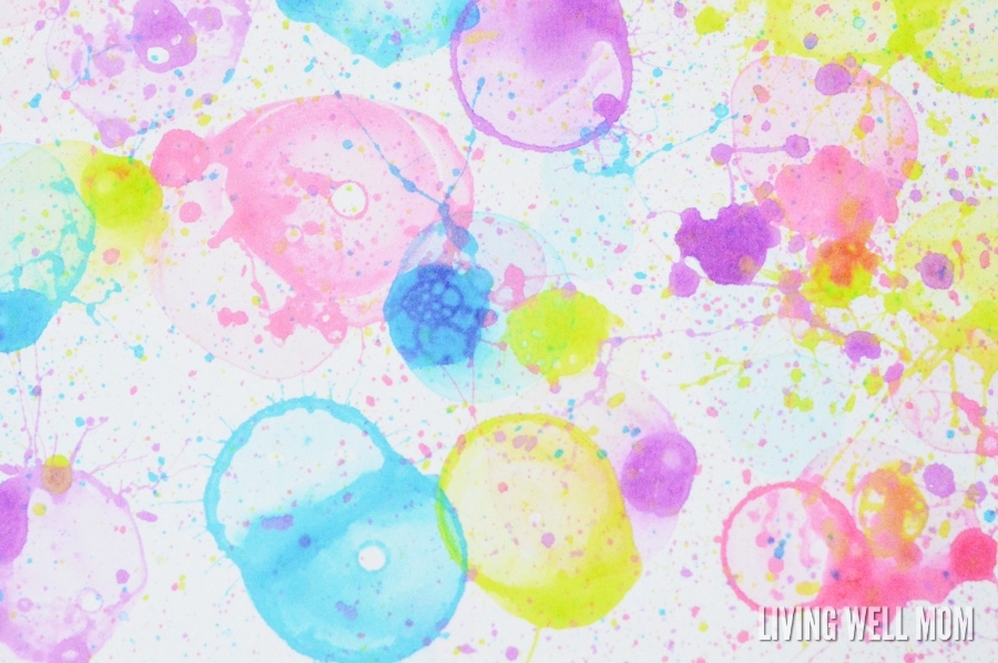A large piece of white card stock with splattered bubble paint art covering the surface. 