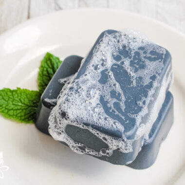 sudsy charcoal soap on a white plate with mint leaves