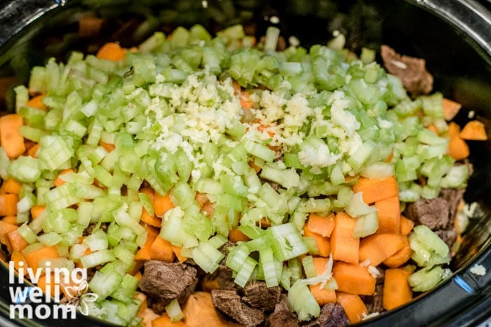 adding celery, carrots, and garlic to crockpot 