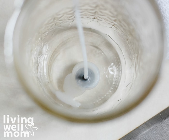 a starter wick sitting in a glass jar being prepped to make a Christmas candle