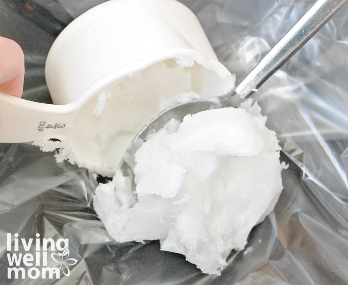 Scooping out coconut oil from a measuring cup.