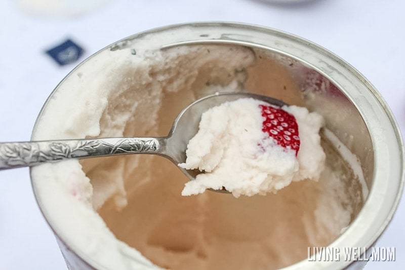 A coffee can of homemade ice cream with strawberries; a spoon is scooping up a bite.