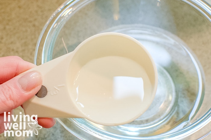 Woman measuring out solution to clean the microwave with vinegar