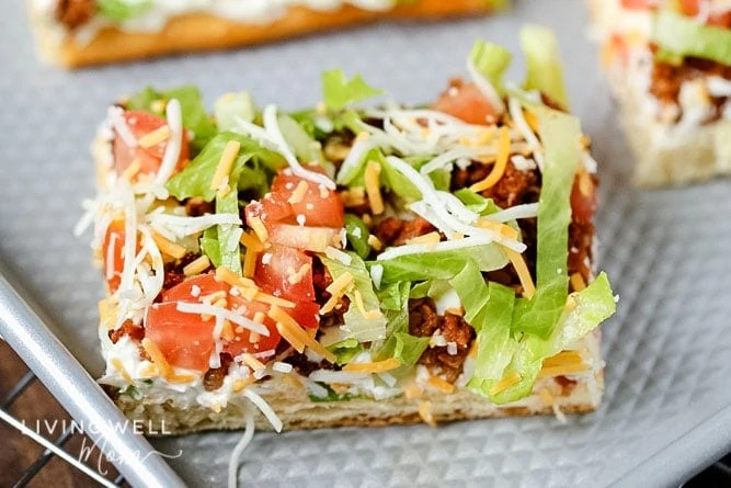 Slice of taco pizza with lettuce and tomato on top