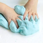 child's hands squishing homemade fluffy blue slime