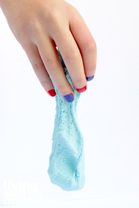 Girl with painted nails playing with fluffy slime made without borax.