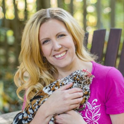 blonde woman in pink shirt holding a colorful chicken