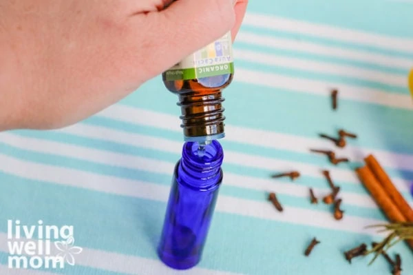 woman adding essential oil to a roller bottle
