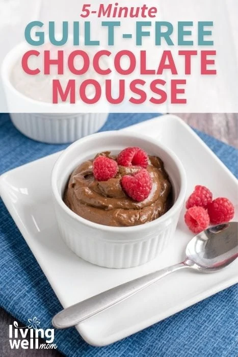 chocolate mousse with raspberries in a white ramekin bowl on a plate with a spoon