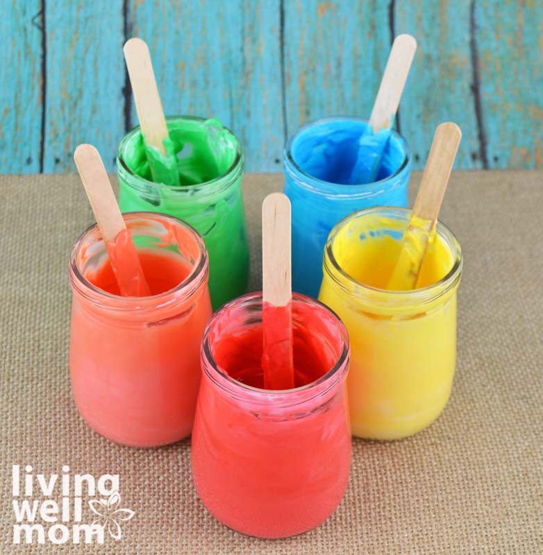 Jars of edible finger paints with popsicle sticks in each, perfect for a messy outdoor painting activity. 