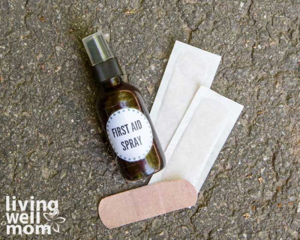 Bottle of diy first aid spray on pavement with bandaids next to it