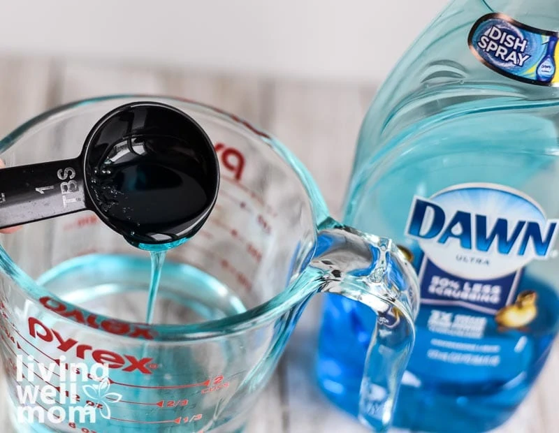 adding dawn dish soap to glass measuring cup - shower cleaner recipe