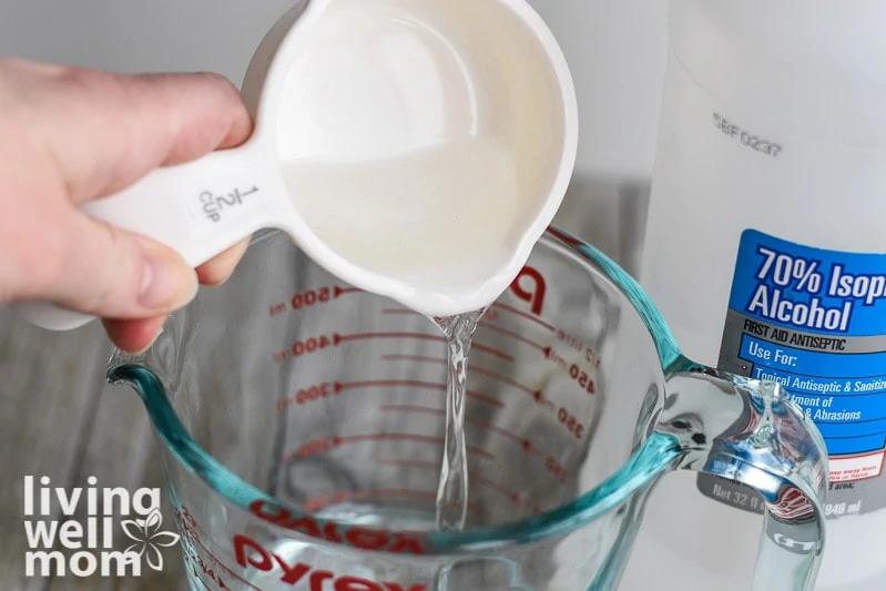 pouring rubbing alcohol into a glass measuring cup