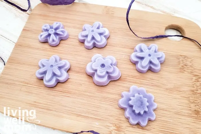 Assorted flower shaped DIY lotion bars displayed on a wooden board. 