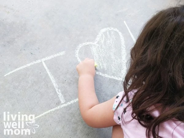 Child coloring in a heart with DIY chalk