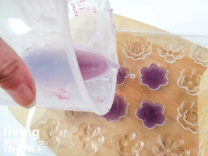 Lavender lotion bar mixture carefully poured into small flower shaped molds in a tray. 