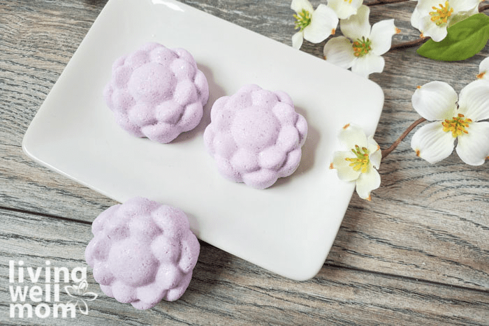 A ceramic tray topped with three purple bath bombs. 