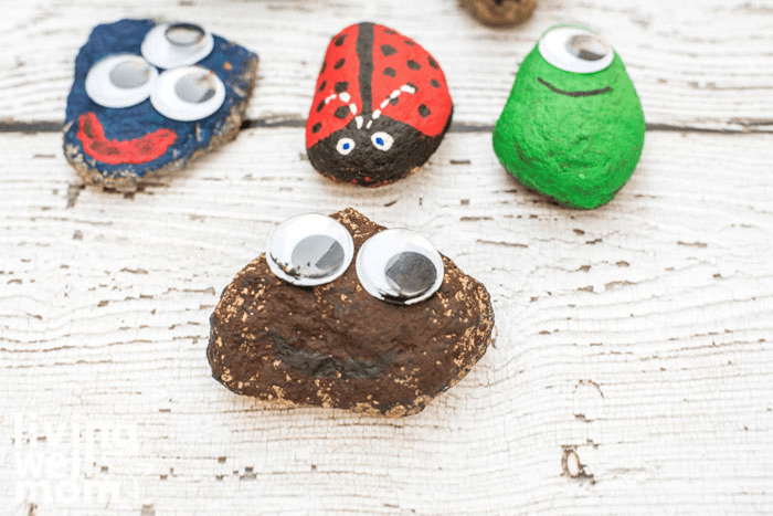 4 painted pet rocks on a table, with googly eyes attached. 