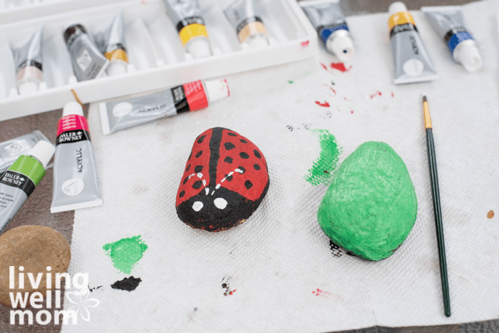 Paper towels on a surface, with acrylic paints and paintbrushes ready for a painted rock craft. 