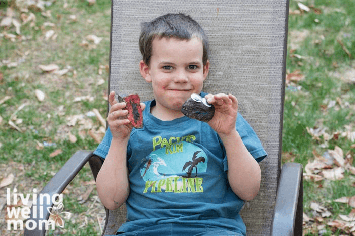 A child sitting in a chair holding two pet rocks. 