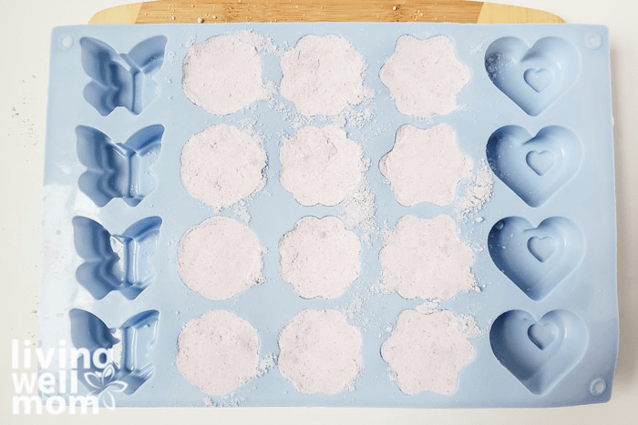A silicone tray filled with moistened mixture for homemade bath bombs. 