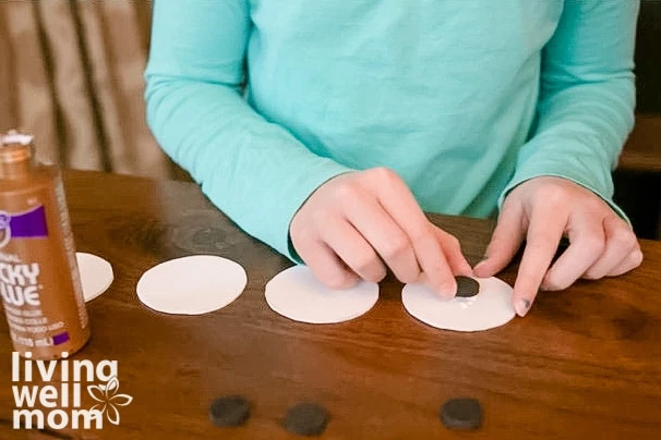 young girl creating snowman bodies with magnets and foam cutouts