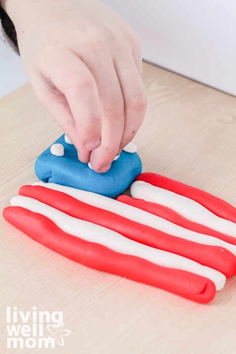 Child adding stars to an American flag made out of playdough