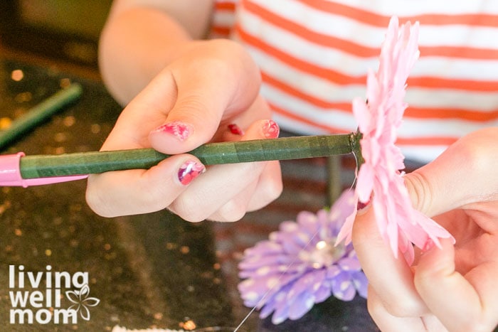 Child attaching a flower to a pen