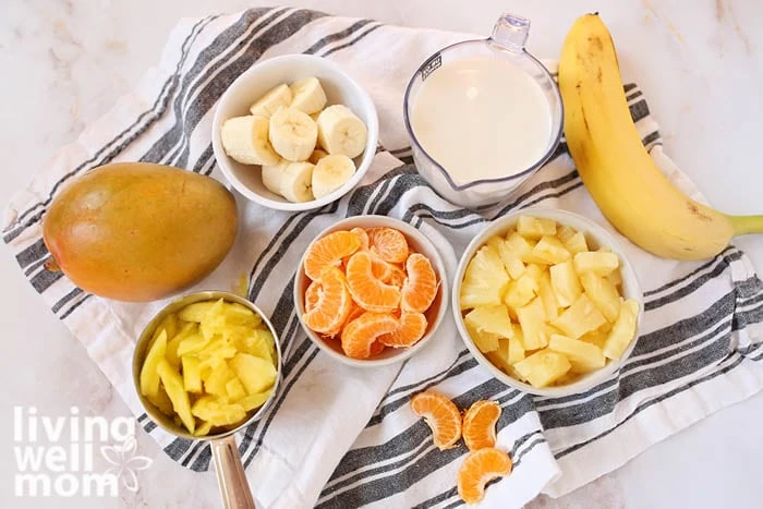 Ingredients for a mango pineapple smoothie in individual bowls