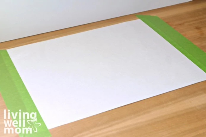 A large sheet of white paper taped to a tabletop as a canvas for finger painting.
