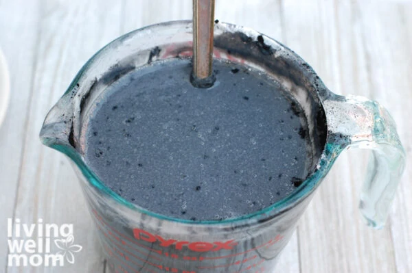 Soap base with activated charcoal in it mixed together in a glass measuring cup