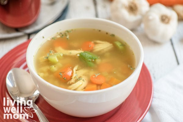 White bowl filled with a soup that has chicken, broth, and veggies