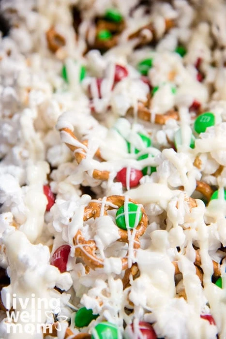 White chocolate popcorn recipe mixed with m&ms and pretzels on a baking sheet