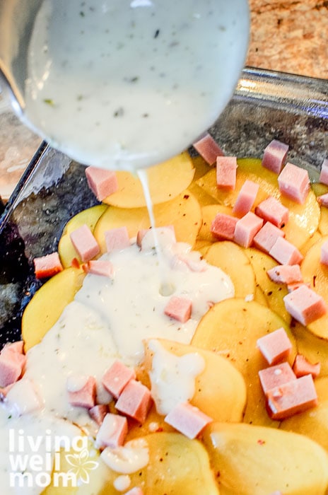 pouring sauce over potato and ham dish