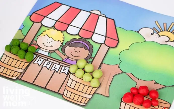 A free printable apple tree activity mat with baskets full of multicolored playdough apples. 