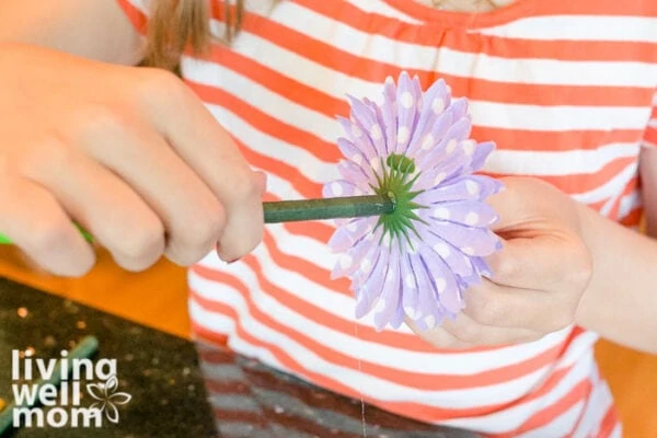 Purple flower being attached to a pen