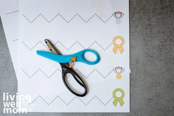Children's safety scissors laid on top of fun and free printable scissor skills sheet. 