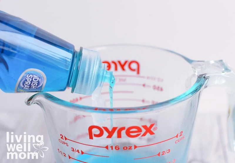 pouring dawn dish soap into glass measuring cup