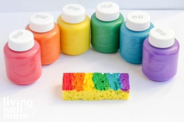 Colorful non-toxic paints fanned out next to a sponge