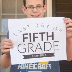 smiling boy with glasses holding up last day of school fifth grade sign