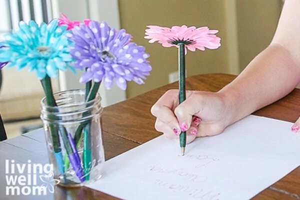 Girl writing a note with a pink flower pen